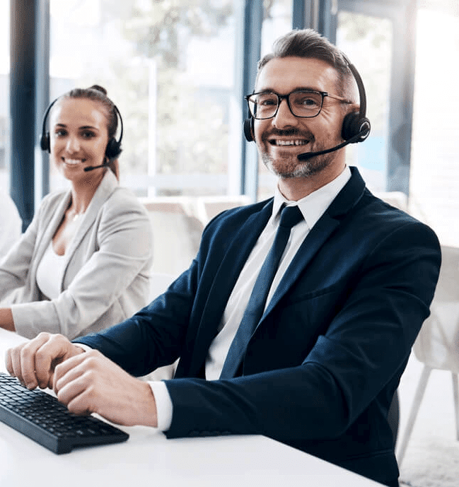 Two individuals at a desk, wearing headsets, representing Prima Consulting’s customer support or consultation team on their ‘Contact Us’ page