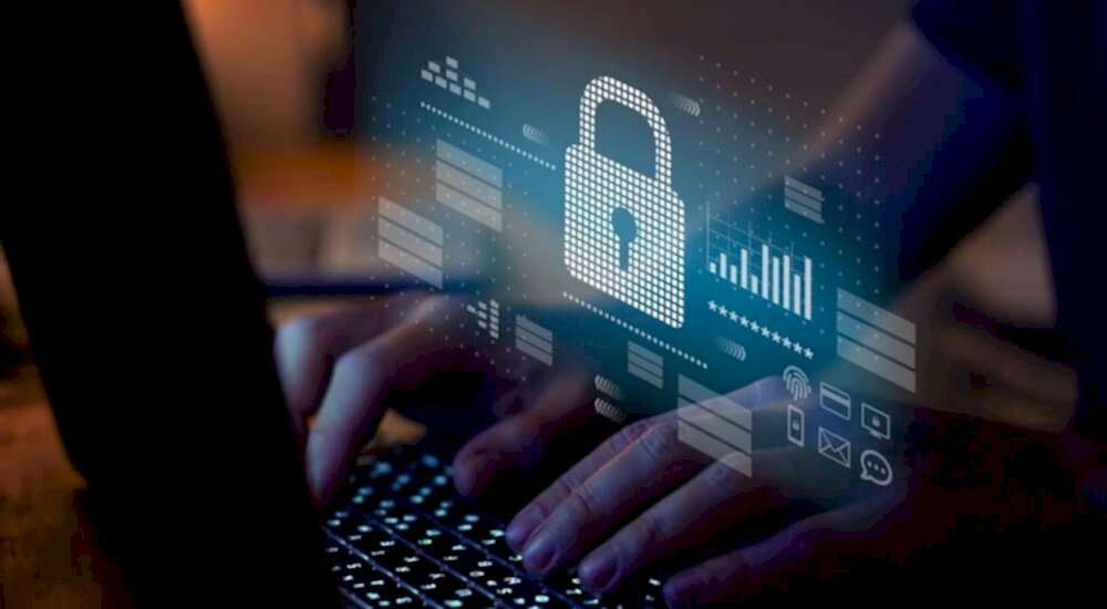 A digital illustration overlays a photograph, depicting a person typing on a laptop keyboard with the screen glowing. In the foreground, there’s a prominent graphic of a padlock symbolizing security, surrounded by various data visualization graphics such as bar graphs and icons representing document security, cloud storage, and encrypted communication. This image conveys the concept of advanced cybersecurity measures in place to protect sensitive employee data managed by software